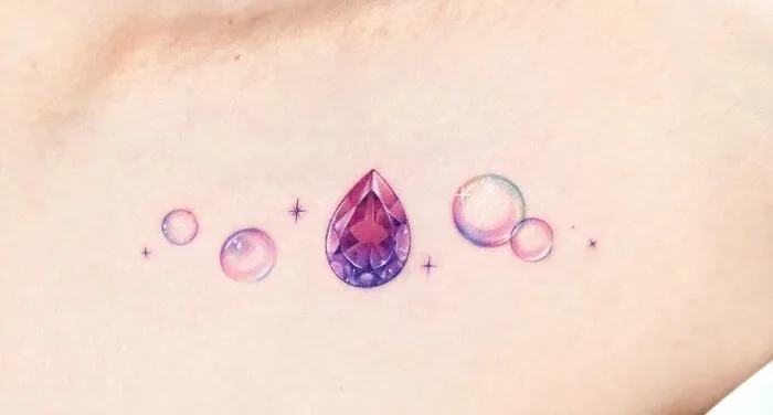 Colorful collarbone tattoo featuring a gem and bubbles, showcasing unique tattoo design for men and women.