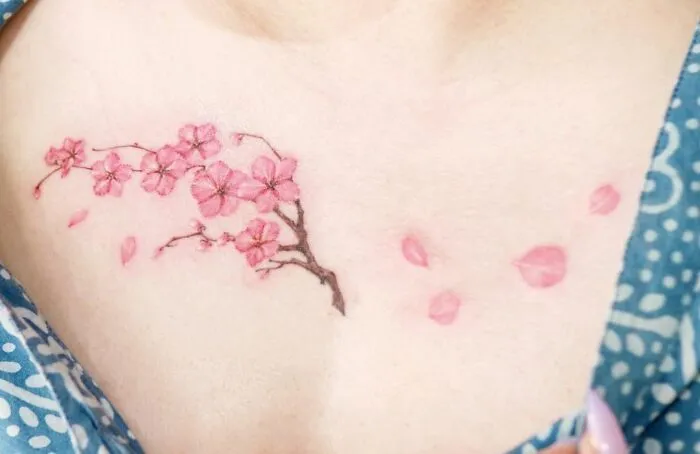 Cherry blossom collarbone tattoo on a person wearing a patterned blue shirt.
