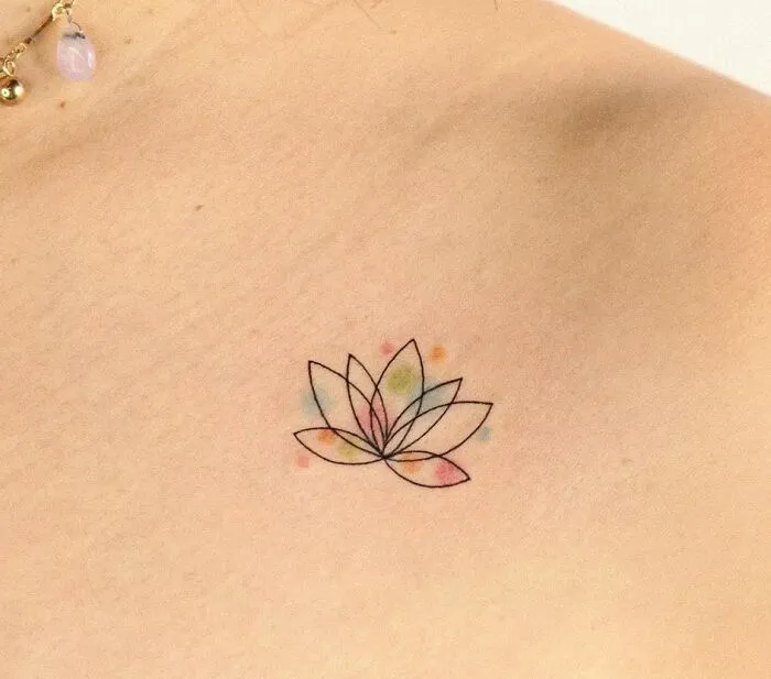 Minimalist lotus collarbone tattoo with subtle watercolor accents.