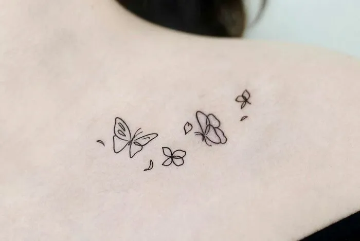 Collarbone tattoo featuring delicate butterflies and flowers for men and women.
