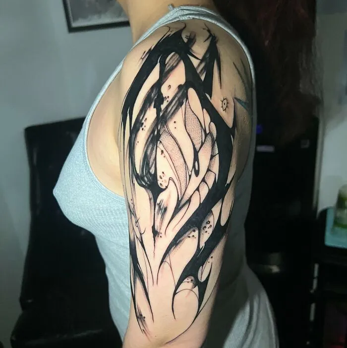 A person wearing a sleeveless top showcasing an intricate tribal tattoo design on their arm.