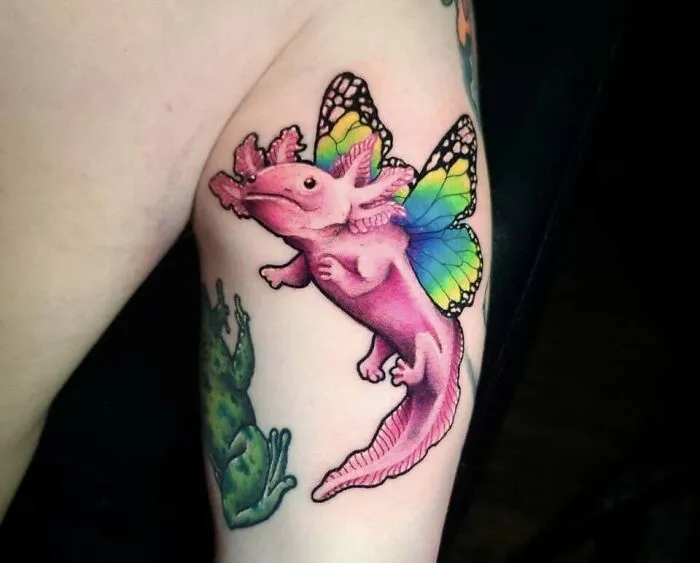 Colorful butterfly tattoo featuring a pink creature with rainbow wings on a person's arm.