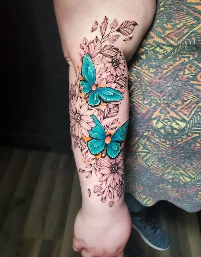 Colorful butterfly tattoos with floral design on forearm.