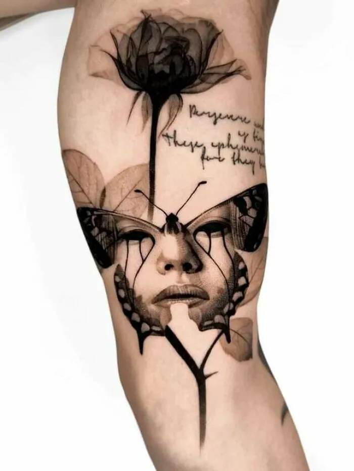 Artistic butterfly tattoo with a face and floral design on the arm.