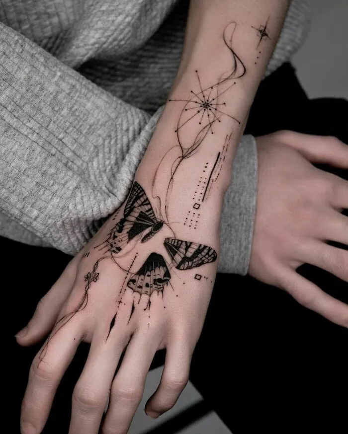 Geometric butterfly tattoo on forearm with intricate designs, showcasing creative and artistic detail.