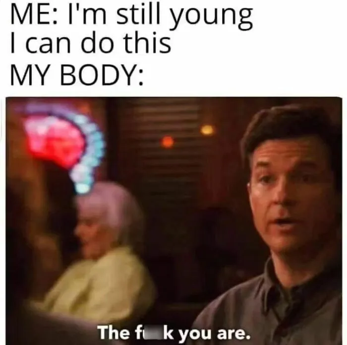 Man in dimly lit room with caption humorously contrasting youthful confidence and physical reality, relatable introvert meme content.