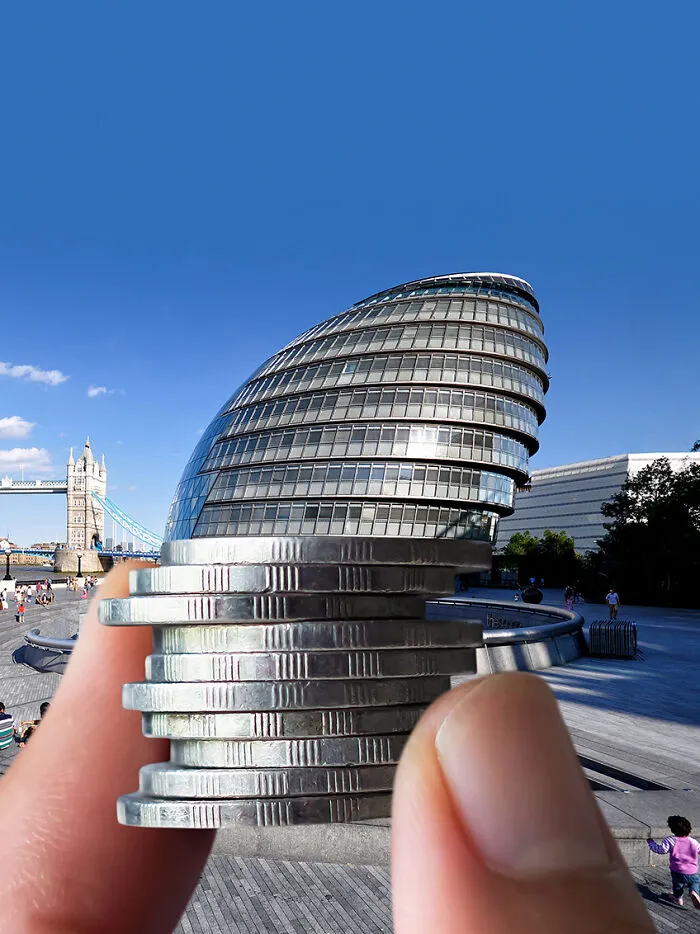 Hand holding coins to play with perspective, aligning them with a building.