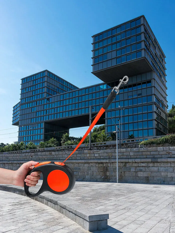 Playing with perspective: A hand holding a dog leash that appears to be attached to a modern building, changing what we see.