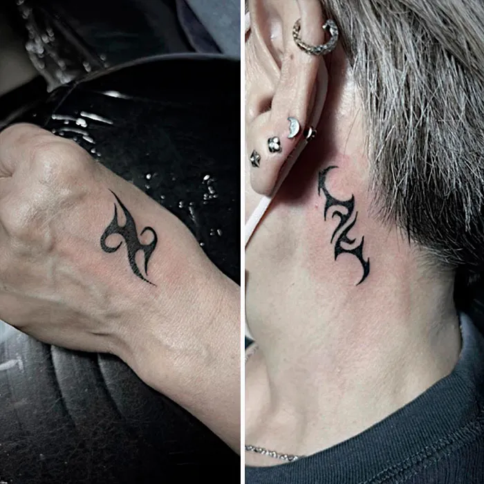 Tribal tattoos on wrist and behind ear, showcasing black ink designs.