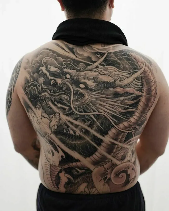 Intricate dragon tattoo covering entire back, showcasing detailed scales and fierce expression.