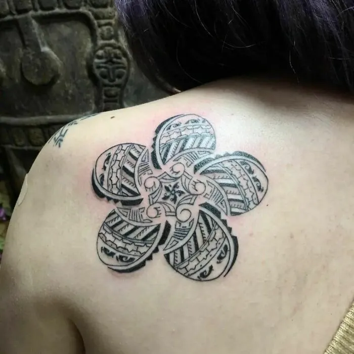 Intricate tribal tattoo design on shoulder, featuring a geometric flower pattern.