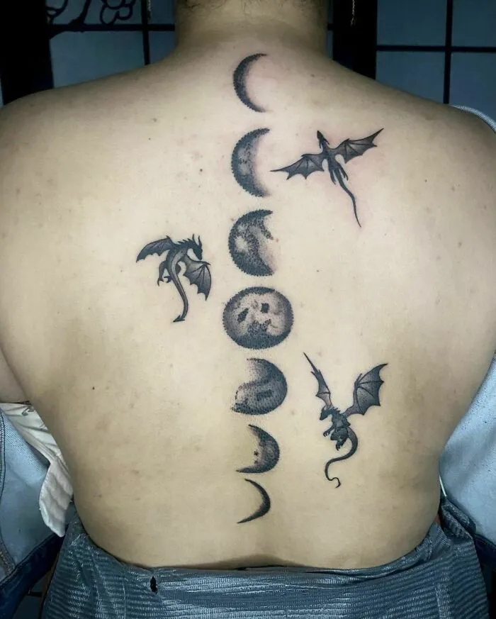 Dragon tattoo with moon phases on back, showcasing unique design elements.