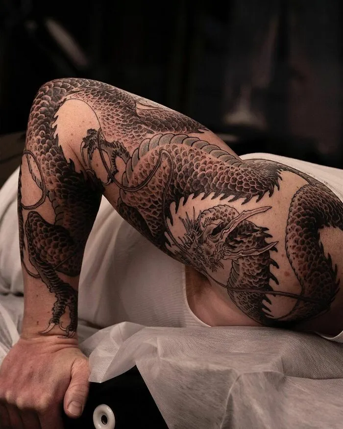 A detailed dragon tattoo design wrapped around an arm, showcasing intricate scales and fierce expression.