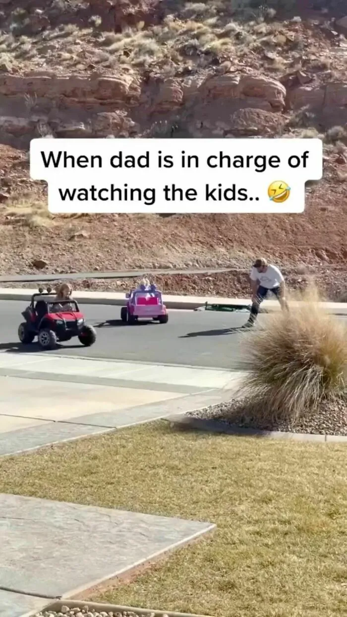 Dad supervising kids in toy cars on a sunny day, showcasing classic dad moves.