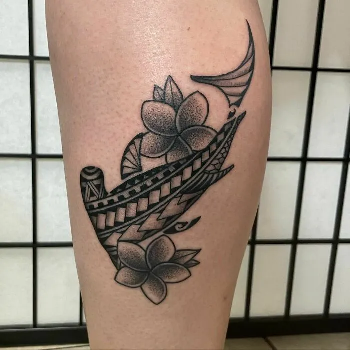 Tribal tattoo featuring geometric designs and floral elements on a leg against a tiled background.