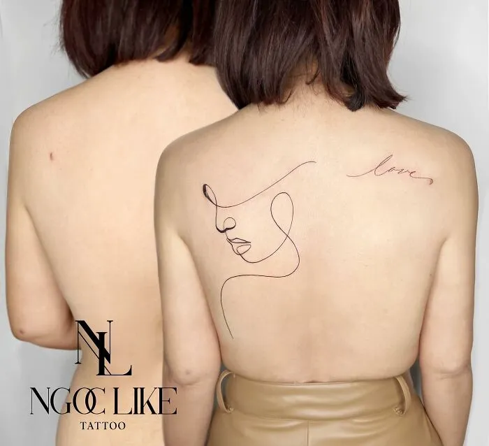 Tattoo artist covers back scars with elegant line art and 'love' script tattoo.