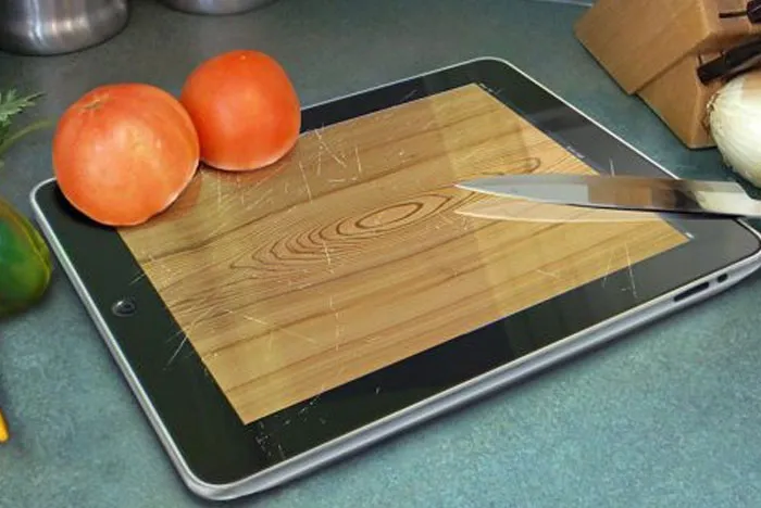 Cursed image of an iPad used as a cutting board with tomatoes and a knife on it.