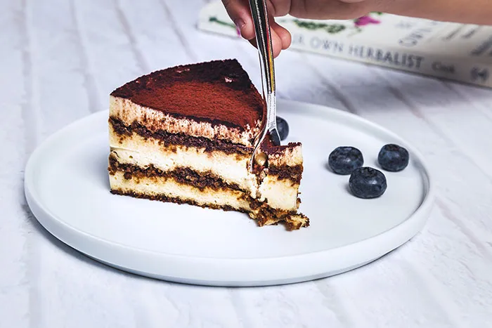 A slice of tiramisu cake with a fork, representing the rich food history behind classic desserts.