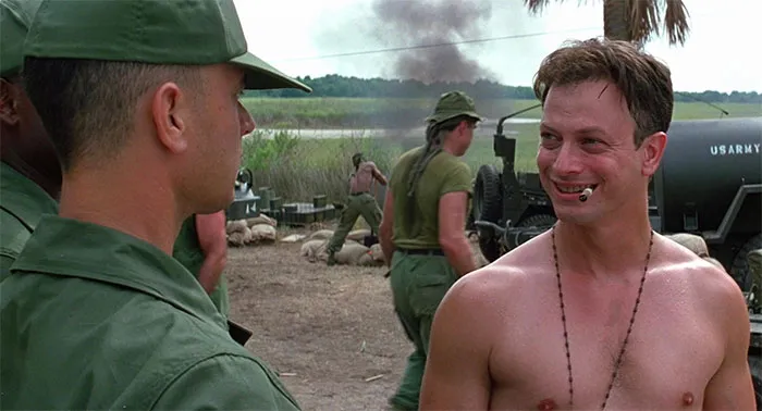 Lieutenant Daniel Taylor smoking a cigar with other soldiers in a military camp, featuring Forrest Gump quotes theme.