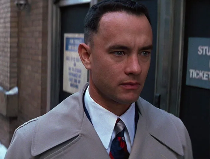 Forrest Gump wearing a grey coat and tie, showcasing iconic Forrest Gump quotes and memorable movie moments.