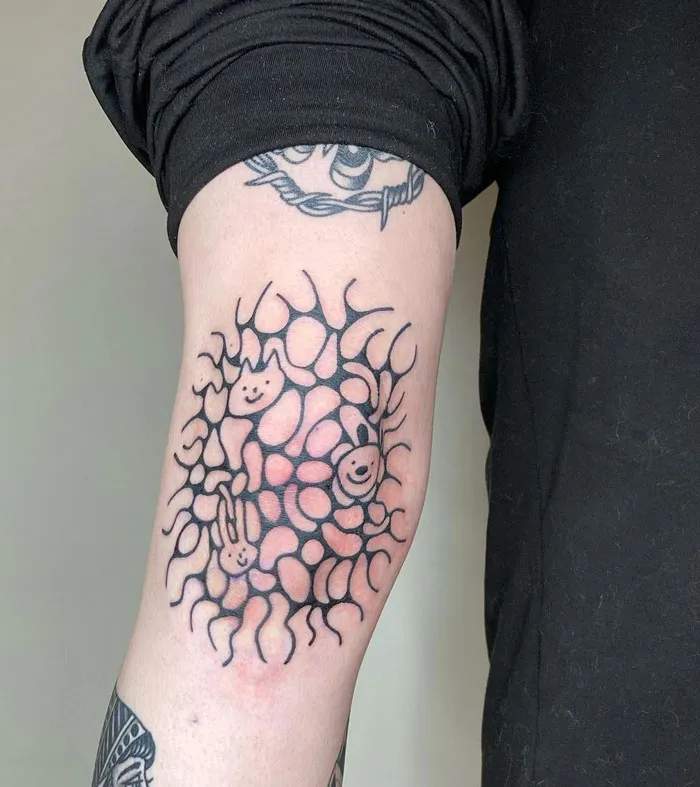 Knee tattoo featuring abstract design with faces and patterns on a person's leg.