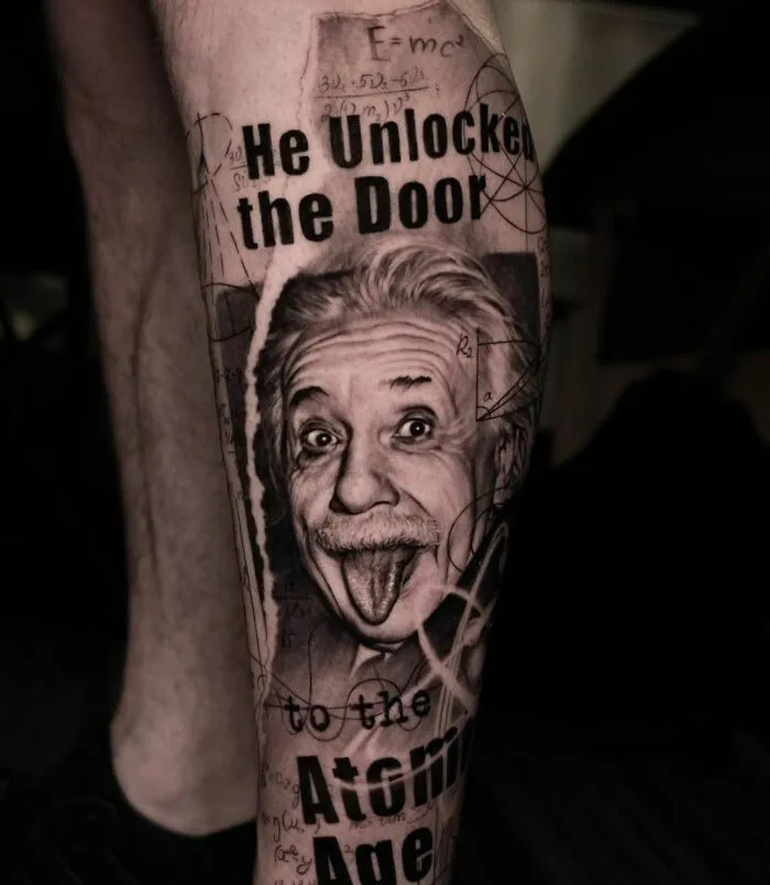 Science tattoo of Albert Einstein with mathematical equations, featuring the phrase "He unlocked the door to the atomic age" on a leg.