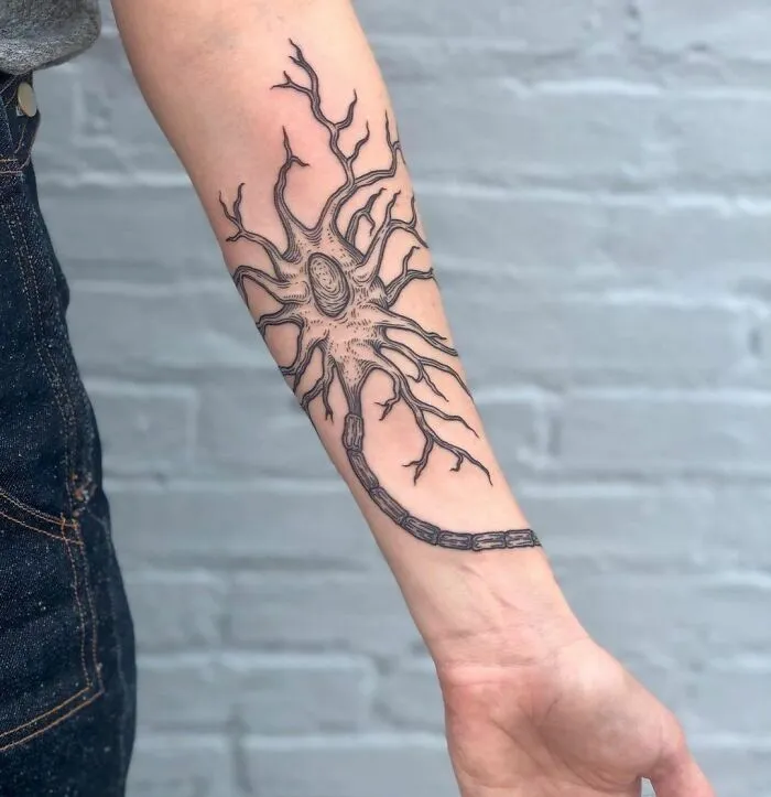 Tattoo of a neuron on a forearm, showcasing a detailed science-inspired design.