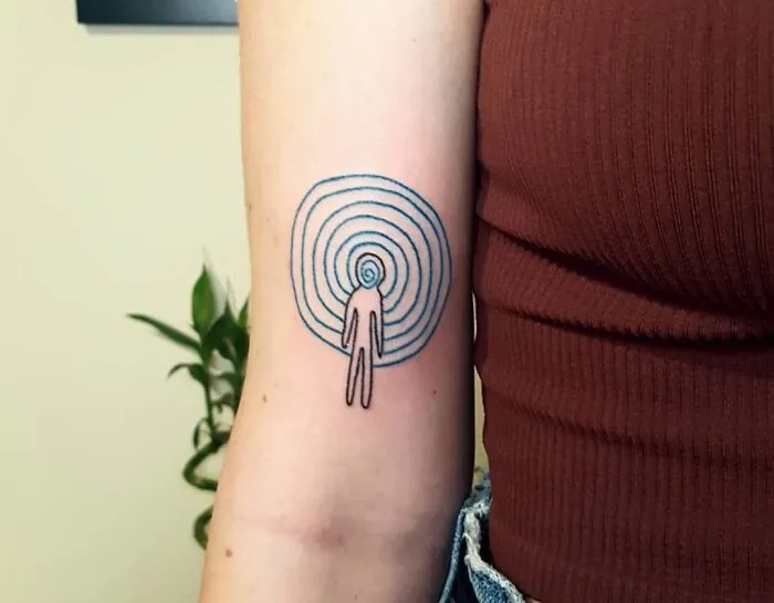 Minimalist mental health tattoo with concentric circles and a figure on an arm, symbolizing healing and inner journey.