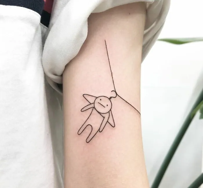 Minimalist mental health tattoo featuring a simple figure hanging from a line, symbolizing healing and resilience.