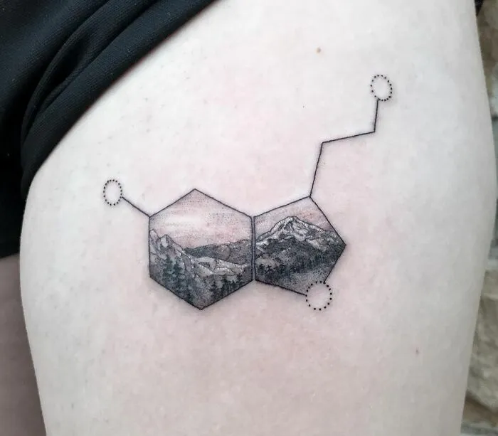 Mental health tattoo of a serotonin molecule with mountain landscape design on skin.