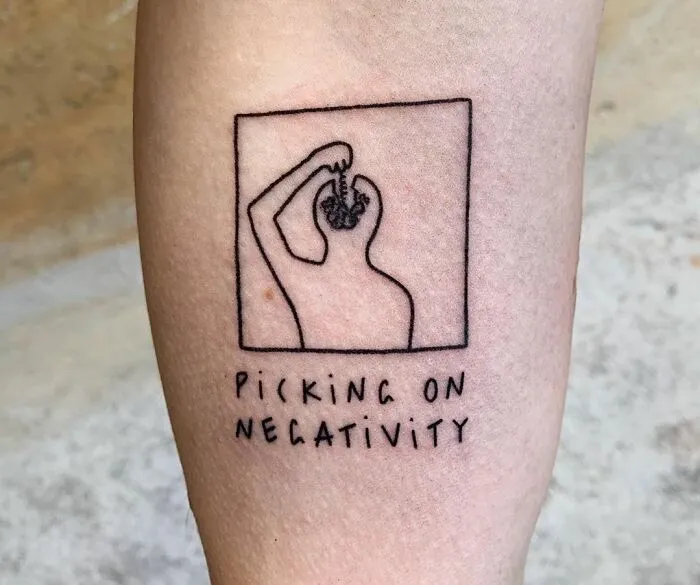 Minimalist tattoo of a figure with text "Picking on Negativity," symbolizing mental health healing.