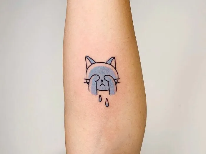 Crying cat tattoo on forearm, symbolizing mental health healing.