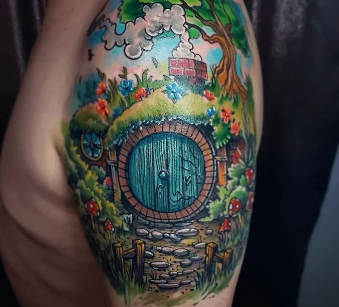 Colorful Hobbit door tattoo from Lord of the Rings with flowers and greenery surrounding it.