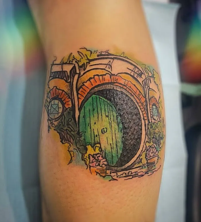Lord of the Rings tattoo featuring a colorful Hobbit door on someone's arm.