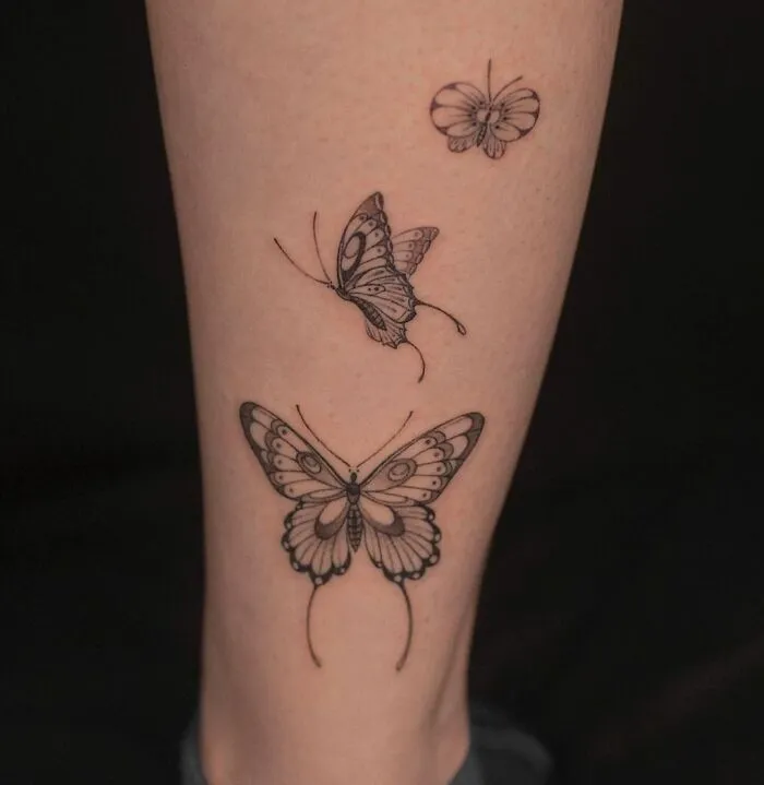 Three butterfly tattoos on a leg, intricately designed with detailed patterns.