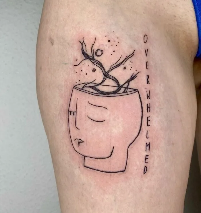 Minimalist mental health tattoo depicting a face with an open head and growing branches, symbolizing being overwhelmed.