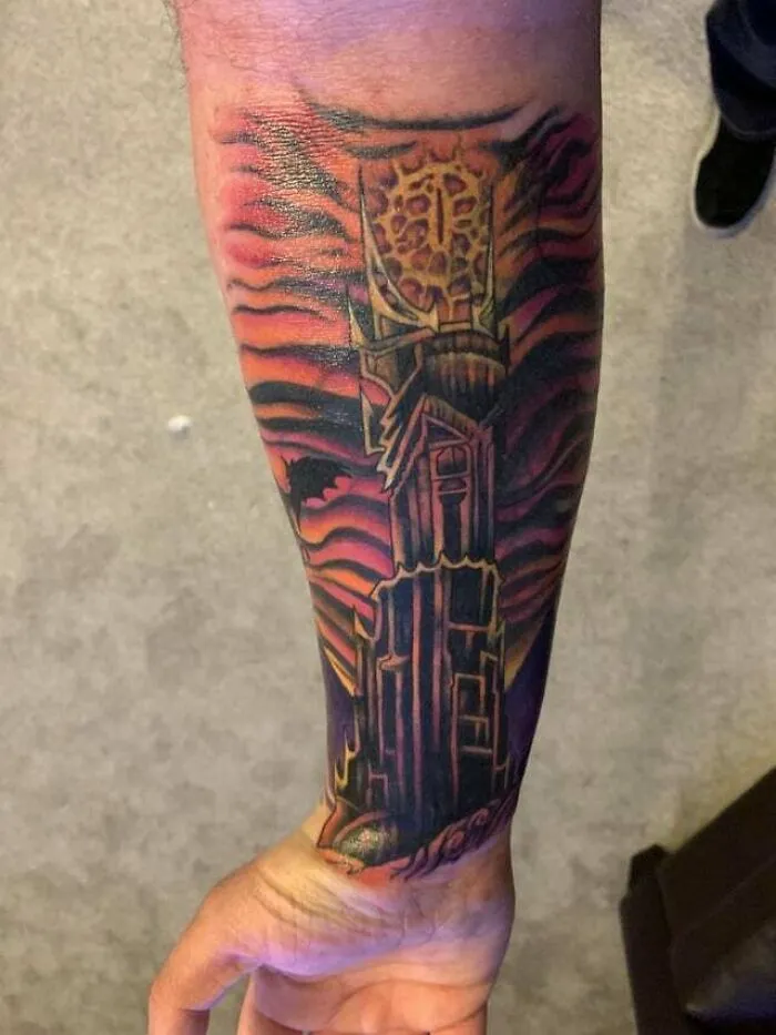 Forearm tattoo featuring the Eye of Sauron from Lord of the Rings, with a fiery design background.