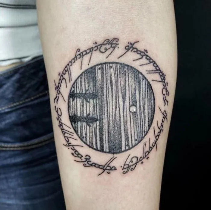 Circular Lord of the Rings tattoo with Elvish script on an arm.