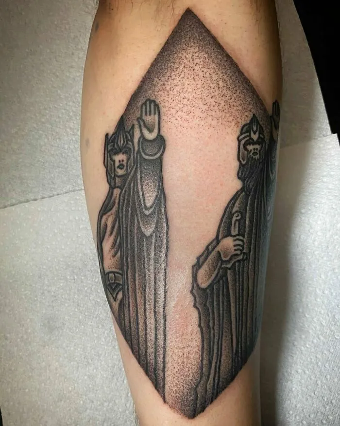 "Detailed Lord of the Rings tattoo depicting iconic characters on an arm in black ink, showcasing intricate artistry."