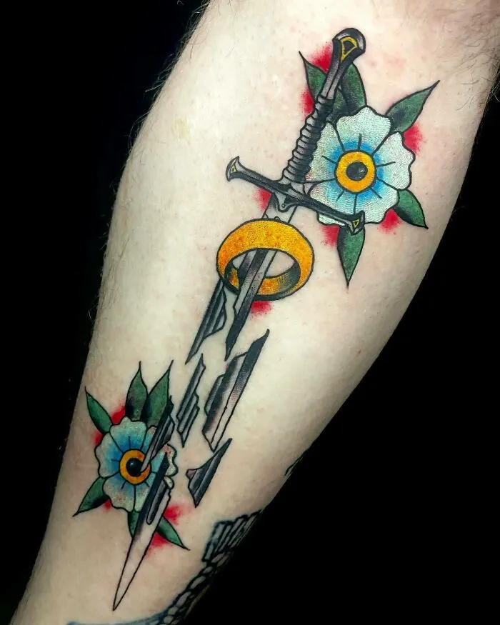 Sword and ring tattoo with flowers inspired by Lord of the Rings.