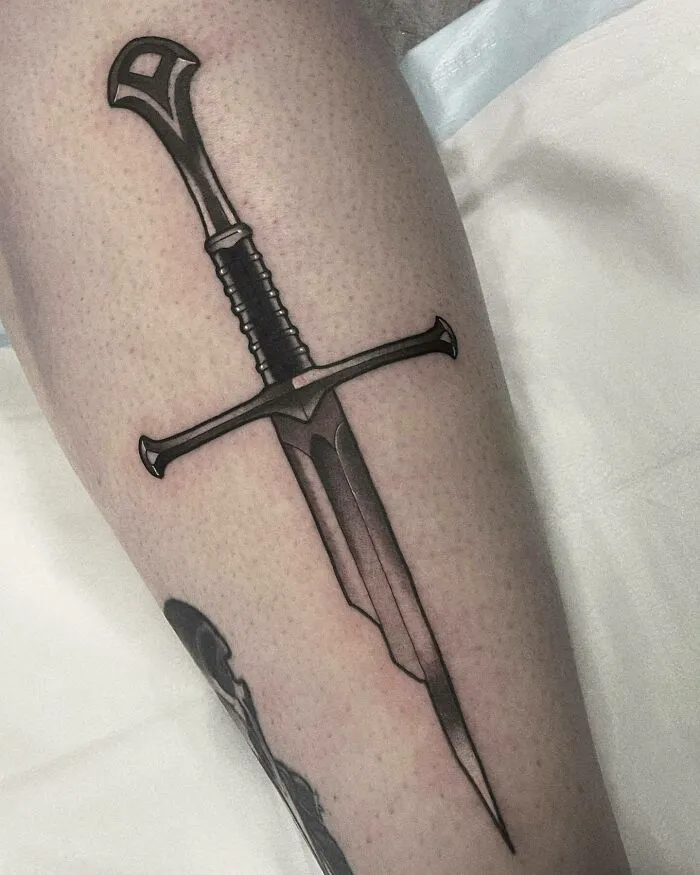Sword tattoo inspired by Lord of the Rings, elegantly designed on a person's leg.