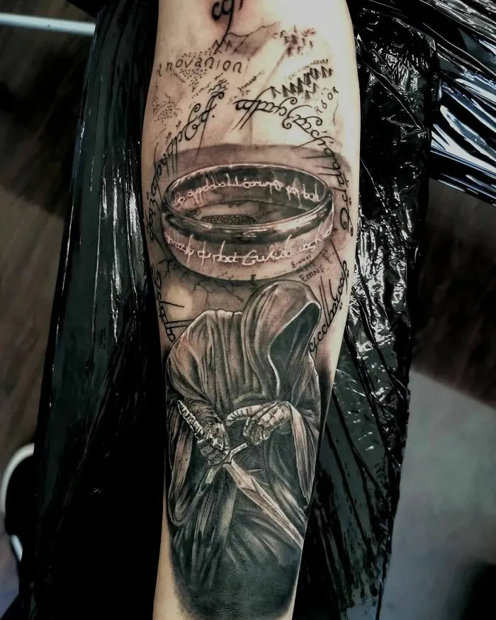Lord of the Rings tattoo with dark-robed figure and inscriptions, featuring the iconic ring design.
