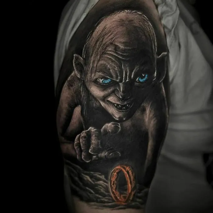 Lord of the Rings tattoo featuring Gollum with blue eyes, reaching toward the One Ring on a dark background.