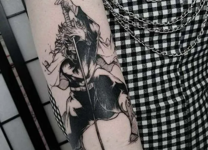 Anime tattoo depicting a character with a sword on an arm, showcasing intricate black and white design.