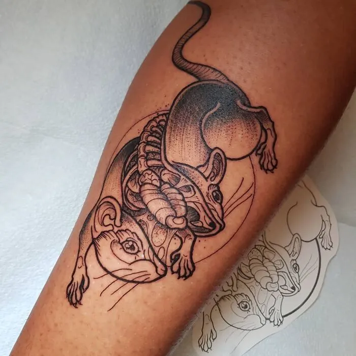 Science tattoo featuring detailed anatomical artwork of intertwined animals on an arm.