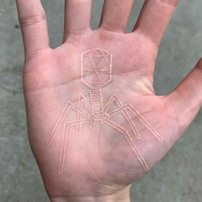 Science tattoo of a bacteriophage design on an open palm, showcasing intricate geometric patterns.