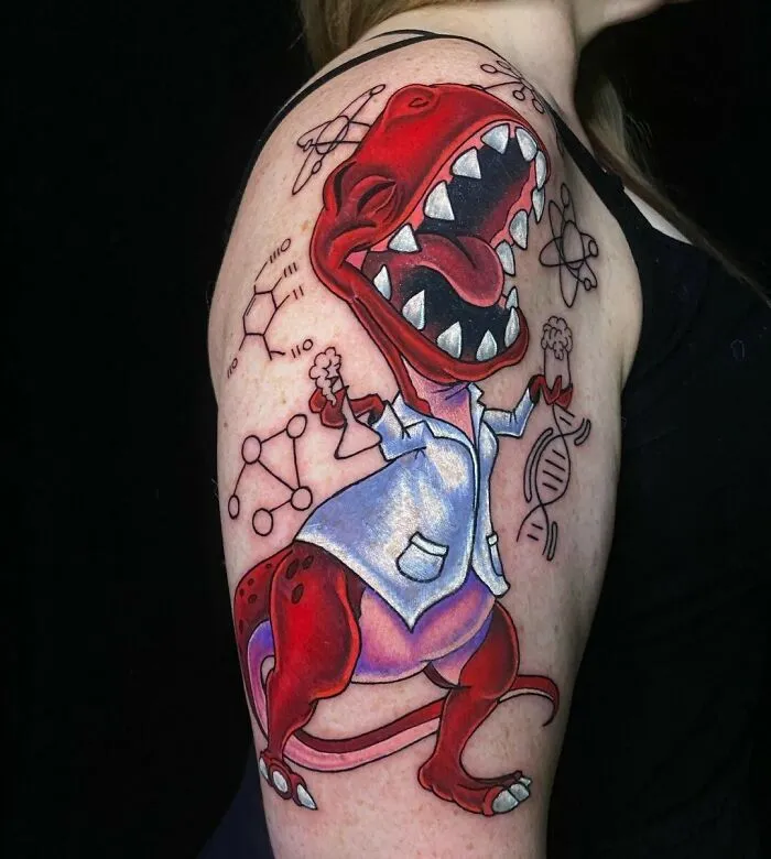 Science tattoos featuring a cartoon dinosaur in a lab coat, holding DNA and molecules, on a person's upper arm.