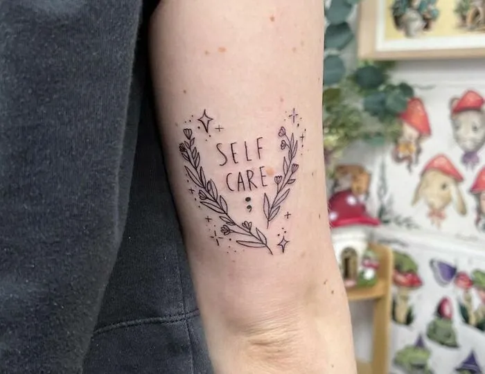 Arm tattoo with floral design and "Self Care" text, symbolizing powerful mental health themes.