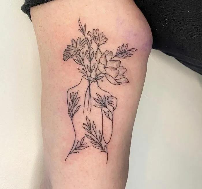Floral outline tattoo of a person, symbolizing growth and healing on an arm, related to mental health tattoos.