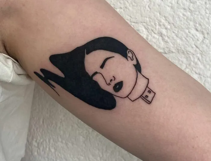 Minimalist mental health tattoo of a USB connection, depicting a woman's face with flowing hair.